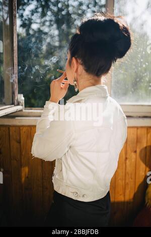 smoking woman on the balcony standing with her back Stock Photo