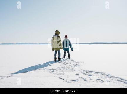 kids walking across a frozen lake in Sweden Stock Photo