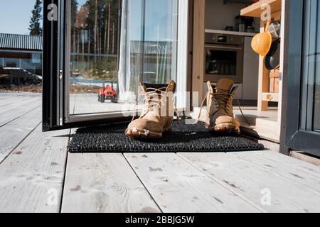 mans boots on a mat at the back door on a balcony at home Stock Photo