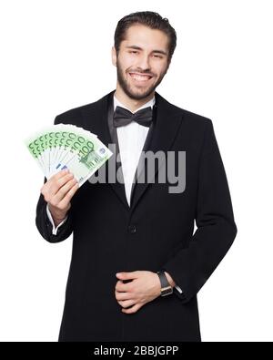 Shark of capitalism. Young male businessman is happy showing euro money. Dressed in a black suit with a bow tie and coat. Stock Photo