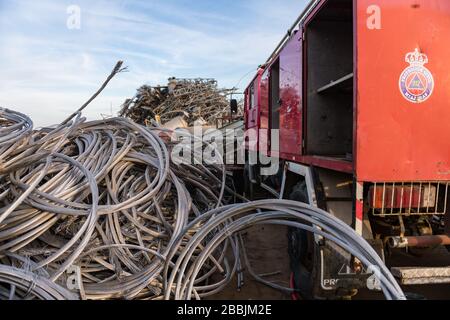 A civil protection truck next to a pile of wire rope coils in a junkyard Stock Photo