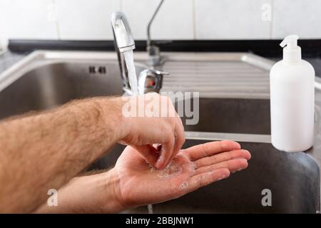Man washing hands with antibacterial soap and water in metal sink for corona virus prevention. Hand hygiene, health care, medical concept. Hand skin Stock Photo