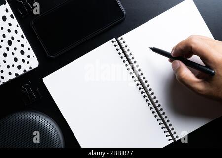 Man hands writing on book in office.Business Man working on desk of black material. Stock Photo