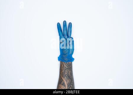 A man hand and gestures in Blue rubber glove shows three fingers sign isolated on white background. Stock Photo