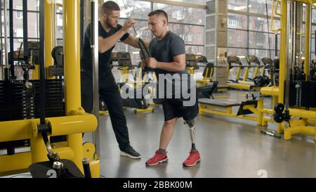Disabled young man with instructor working out in gym Stock Photo
