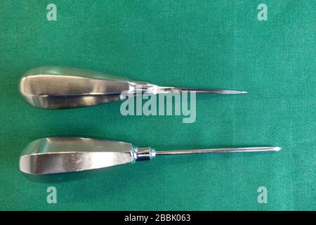 two awls of different sizes lie on a green surgical drape Stock Photo