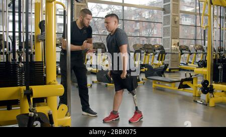 Disabled young man with instructor working out in gym Stock Photo