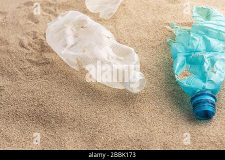 Plastic bottle lies on the beach and pollutes the sea. Spilled garbage on the beach. Empty used dirty plastic Stock Photo