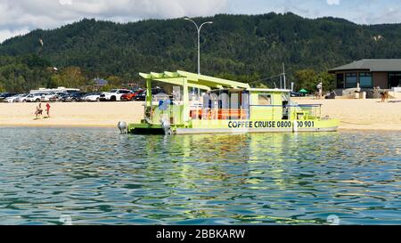 Kaiteriteri, Tasman/New Zealand - March 3, 2017: Coffee and cruise tour operator's green catamaran at Kaiteriteri Beach, Tasman region, New Zealand. Stock Photo