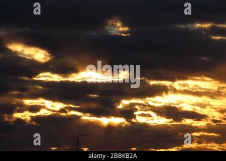 The suns rays pass through the dark clouds. Beautiful dramatic sky at sunset or sunrise. Stock Photo