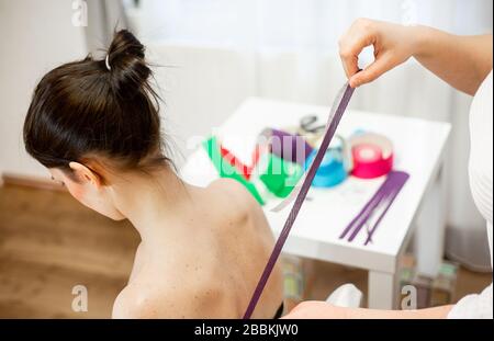 Professional physical therapist applying tape on patients shoulder, kinesiotaping concept Stock Photo