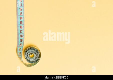 Top view of border frame made of measure tape with empty space for your idea. Sewing and keeping fit concept on orange background. Stock Photo