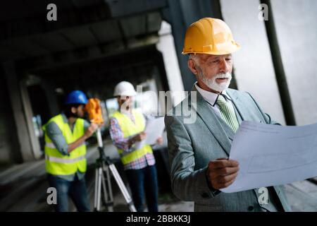 Two satisfied engineers talking at building site with construction structure in background Stock Photo
