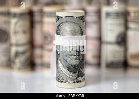 Blindfolded One hundred US dollar rolled bill banknote, with of focus mix rolled dollars banknote background, concept Bribe for Blind, Corruption. Stock Photo