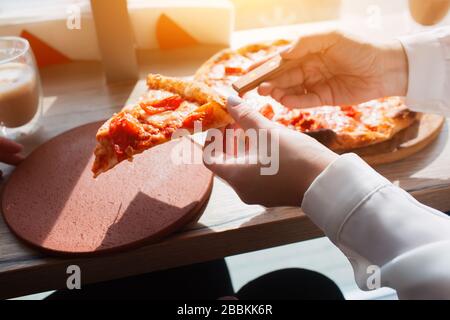 Slice of pizza in hands close-up. Pizza stands on a table in a cafe Stock Photo