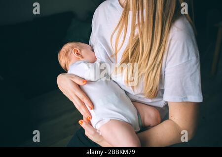 Breastfeeding concept. Portrait of a newborn baby. Mother holds a child in her arms. The first year of life. Care and health. Stock Photo