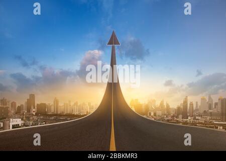 A road turning into an arrow rising upward on city background, symbolizing the direction to success in the future as a symbol of business vision. Stock Photo