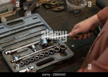 Mechanic take tool from the set tools, wich lying on the desktop in garage Stock Photo