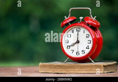 Time management concept - retro red alarm clock standing on a book with copy space Stock Photo