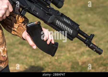 A man is holding a rifle magazine camouflage clothes Stock Photo