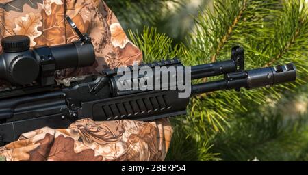 A person is holding a rifle camouflage clothes Stock Photo