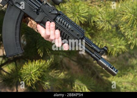 A man is holding a rifle camouflage clothes pine background Stock Photo