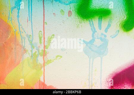 White plastered wall with colorful drips, flows and paint sprays. Handprints on white wall background Stock Photo