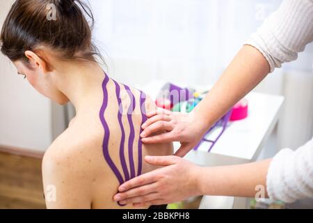 Professional physical therapist applying tape on patients shoulder, kinesiotaping concept Stock Photo