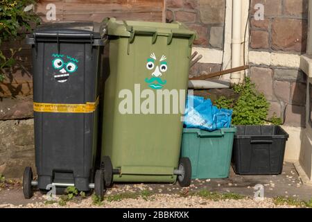 Bristol-March 2020- England-a close up view of a black and green wheeling rubbish bins with a funny face sticker on the side Stock Photo