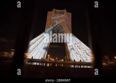 March 31, 2020, Tehran, Iran: A view at night of the lit-up Azadi (Freedom) tower with flags, messages of sympathy from all over the world over the ongoing novel coronavirus disease (COVID-19) pandemic, in Tehran, Iran. The appreciation message was also reflected in healthcare professionals who are trying to stop the pandemic in the country. The light display was organized by the city municipality. According to the latest reports by the Iranian Ministry of Health, over 2,000 people have died from the coronavirus infection throughout the country. (Credit Image: © Rouzbeh Fouladi/ZUMA Wire) Stock Photo