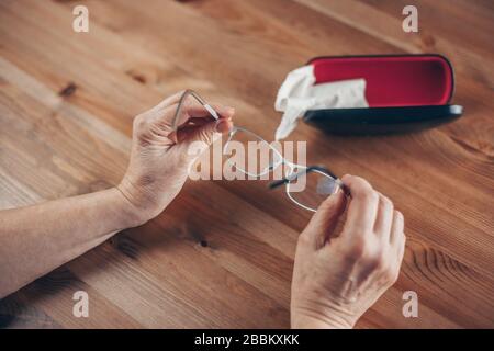 Dirty eyeglasses, woman hand thoroughly cleaning eyeglasses by a cloth, Stock Photo