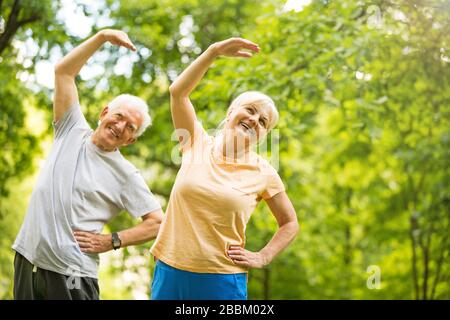 Senior Couple Exercising In Park Stock Photo