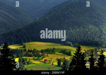 Panoramic view of a Tatra Mountains valley with meadows and farms seen from Toporowa Cyrhla village near Zakopane in Poland Stock Photo