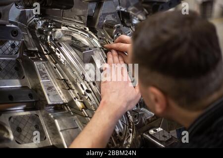 Repairman doing maintenance on the mold injection for plastic components, industrial concept Stock Photo