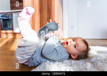 Adorable funny one year old lie on a carpet. Looking into camera. Stock Photo