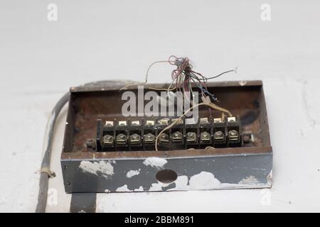 Old electrical distribution box on white wall Stock Photo