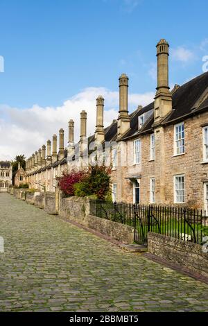 Row of 14th century terraced houses with tall chimneys and small front gardens on cobbled street in Vicars Close, Wells, Mendip, Somerset, England, UK Stock Photo
