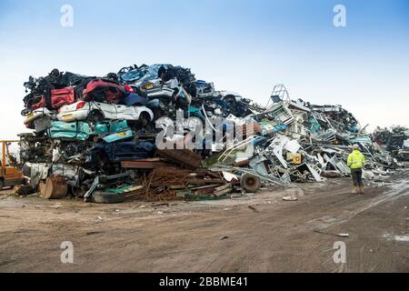 A man stands in front of a pile of scrap metal. Stock Photo
