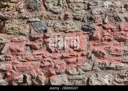 Rough masonry on clay mortar. Surface texture of a stone wall with a strip of red paint, abstract image for background. Stock Photo