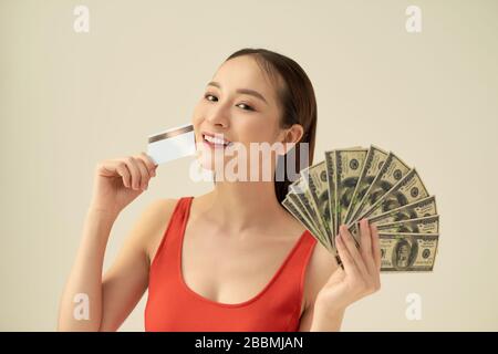 Excited young woman with cash money and credit card on gray background Stock Photo