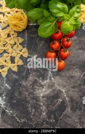 Dry pasta on black marble work top with basil Stock Photo