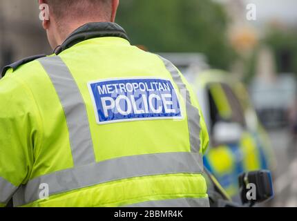 Met.Police officer at a road block on street leading to Parliament Square, London, to stop & divert traffic from an oncoming protest demonstration. Stock Photo