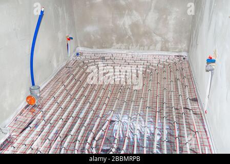 White pipes of underfloor heating systems, distributed in an individual family house on insulating foil. Stock Photo