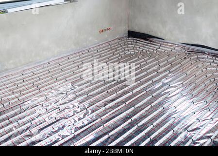 White pipes of underfloor heating systems, distributed in an individual family house on insulating foil. Stock Photo