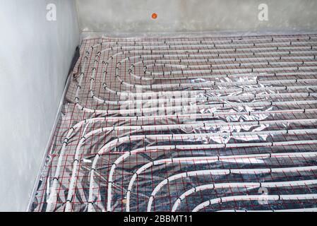 White pipes of underfloor heating systems, distributed in an individual family house on insulating foil. Stock Photo
