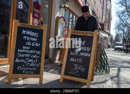 Munich, Germany. 01st Apr, 2020. An Indian cook puts up signs in front of his restaurant in the Haidhausen district. On one of them is written: 'Dear guests, we have everything To Go'. After all restaurants have to remain closed until further notice due to the spread of the coronavirus, many restaurants offer take-away food. Credit: Peter Kneffel/dpa/Alamy Live News Stock Photo