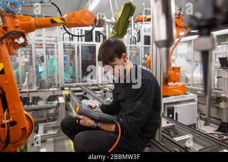 Young man programming industrial automatic robot in automotive industry Stock Photo