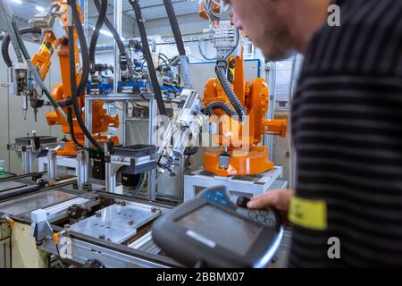 Engineer setting up automatic robot arms in smart factory, automotive industry, industrial concept Stock Photo