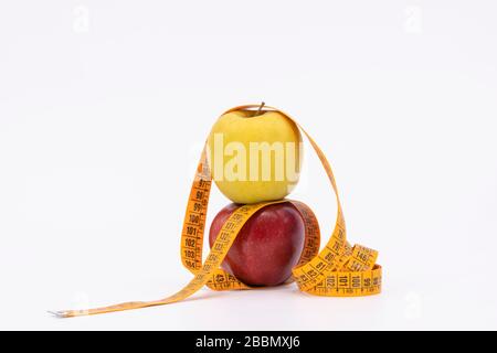 yellow and red apple with measure tape as symbol for diet and weight control Stock Photo