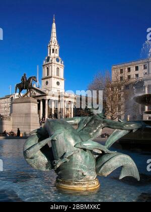 View of the church of St. Martin-in-the-Fields, the equestrian statue of King George IV, and the bronze dolphin in one of the fountains in Trafalgar Square, London, England, UK Stock Photo